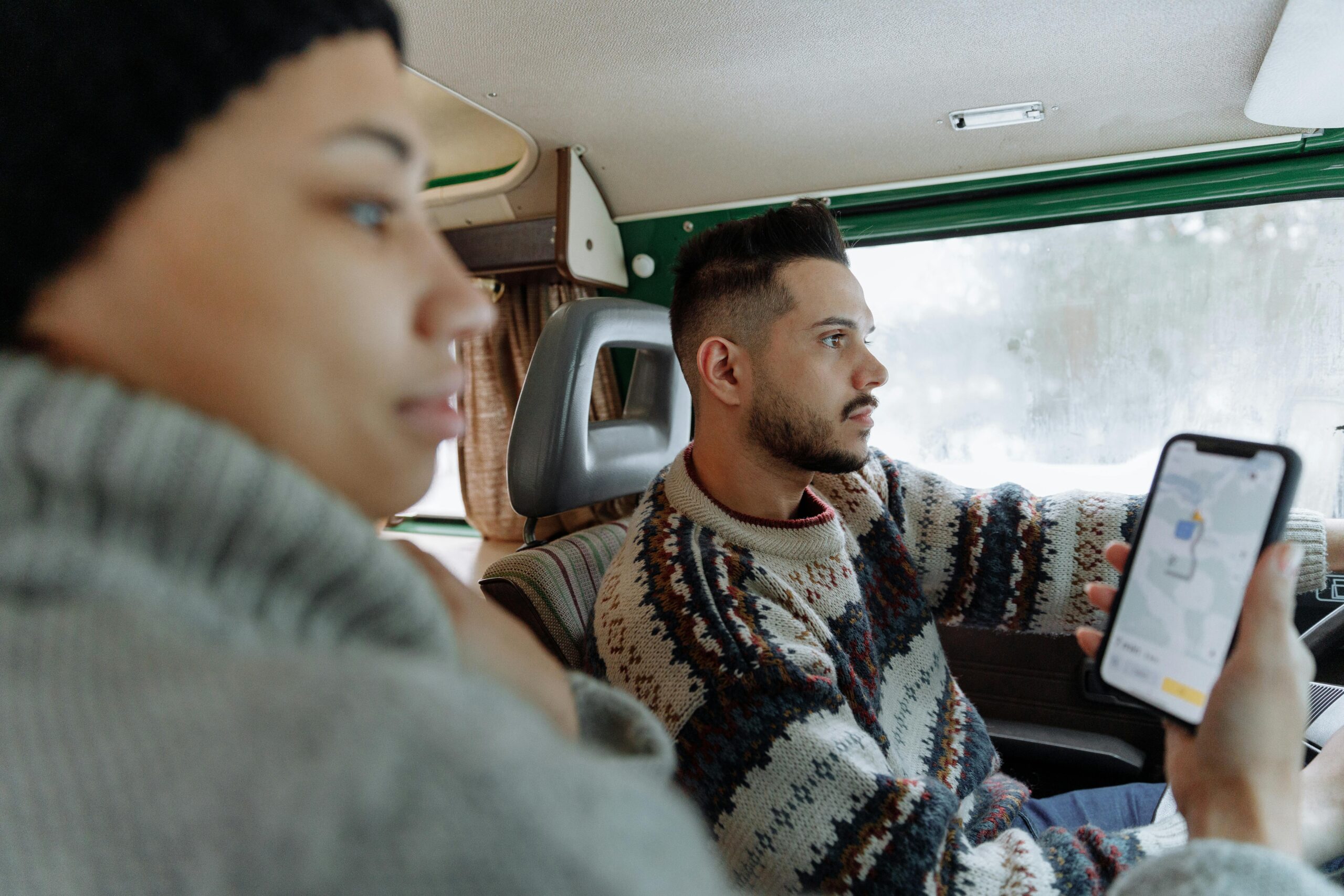 young couple driving camper van with maps
